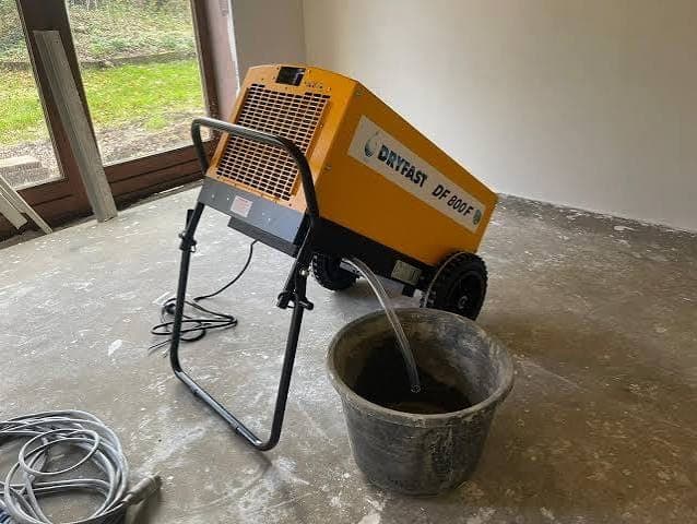 Bouwdroger met condensafvoer naar een emmer tijdens een klus