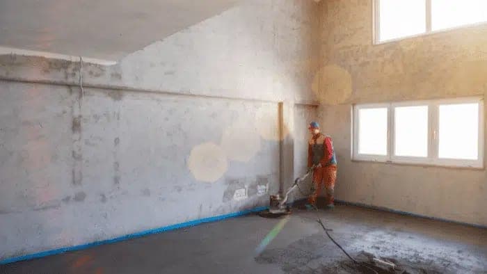 Vakman werkt een verse cementdekvloer af in een nieuwbouwwoning